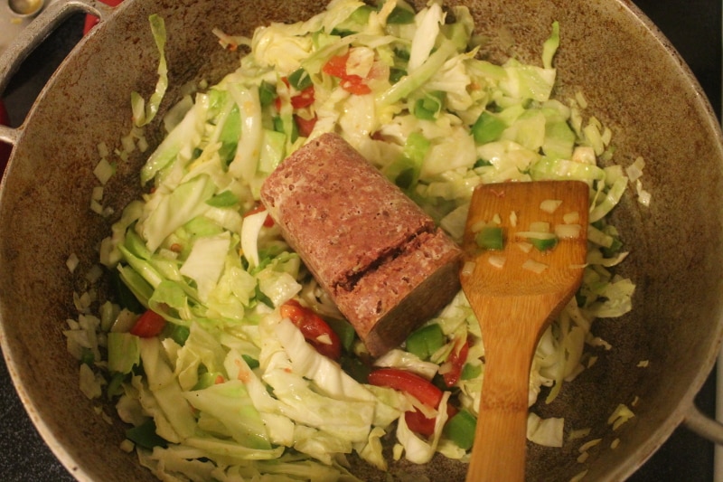 dutch pot with corn beef on top of cabbage and peppers