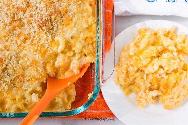 creamy baked macaroni and cheese in pan next to white plate