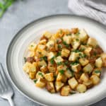 roasted potatoes in white plate with for on side