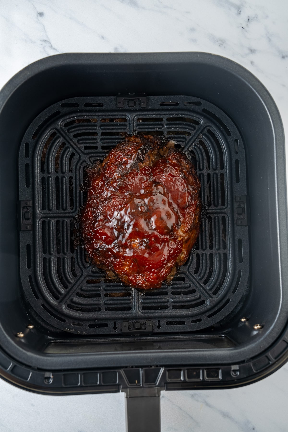 cooked meatloaf with glaze in air fryer basket