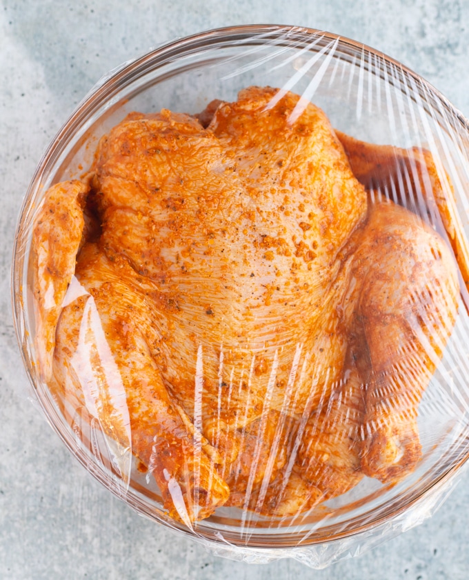 raw whole chicken in bowl in marinade