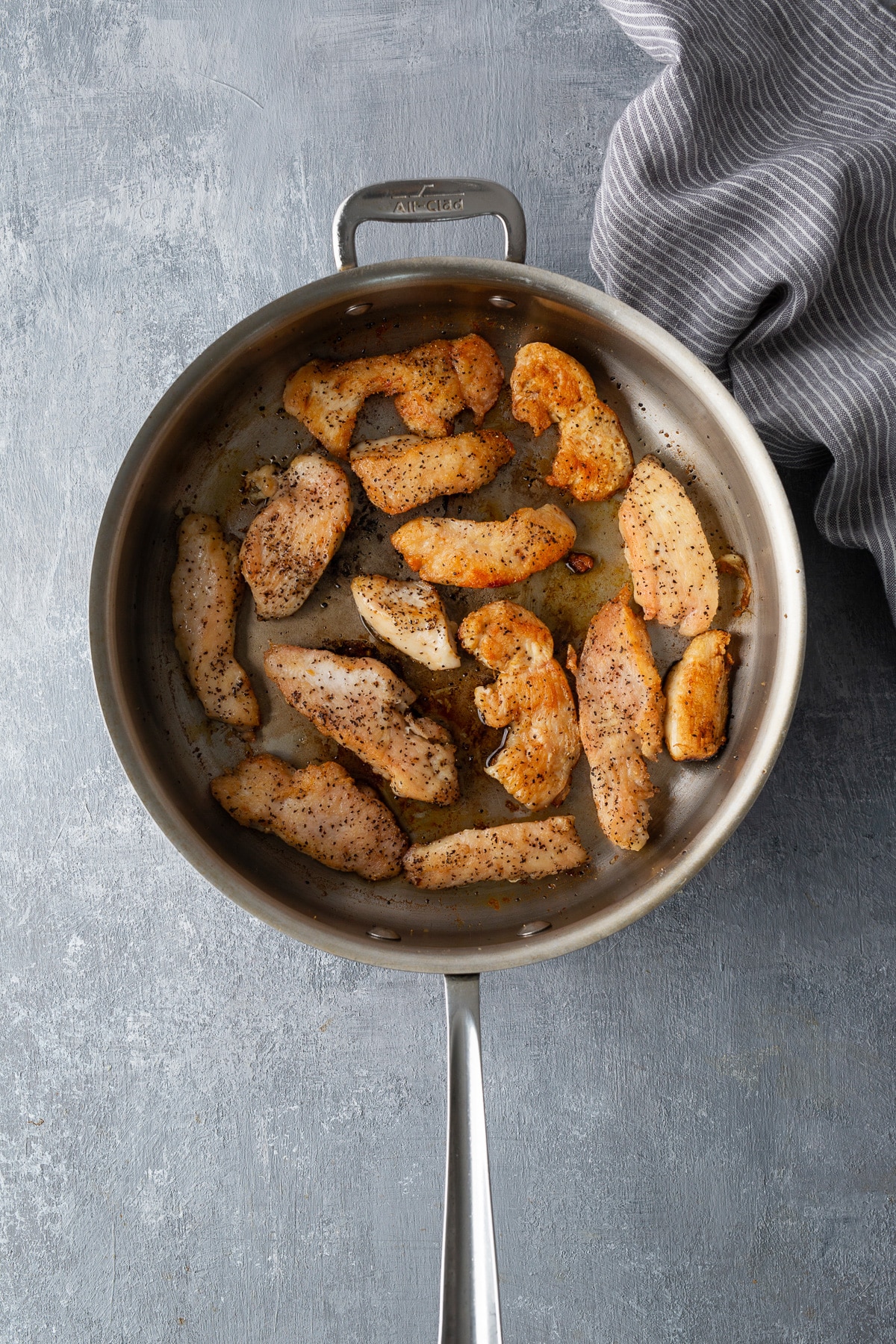 sliced of chicken breast in pan seasoned with salt and pepper