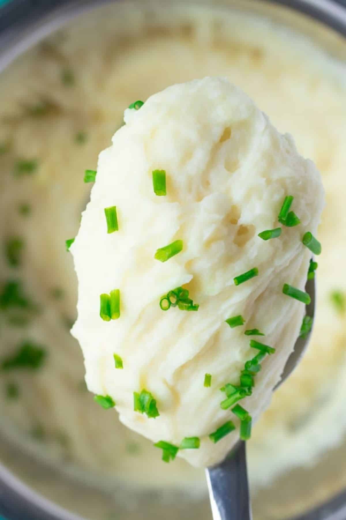 mashed potatoes on spoon with pressure cooker in background