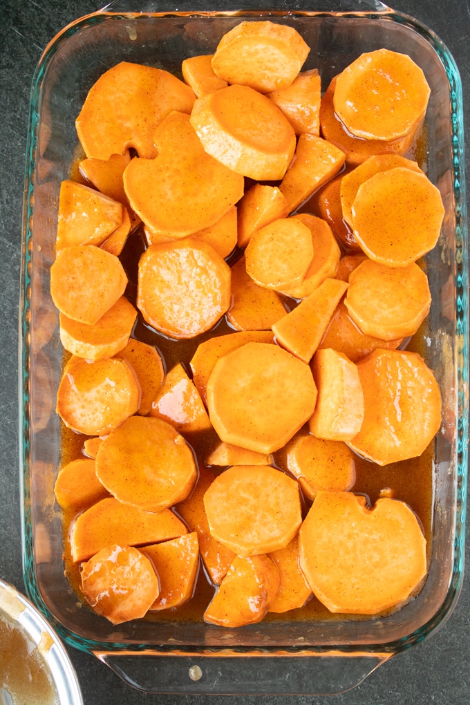 raw sliced sweet potatoes covered in butter sugar mixture