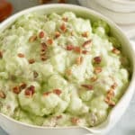 watergate salad in a bowl with pecans and marshmallows in background