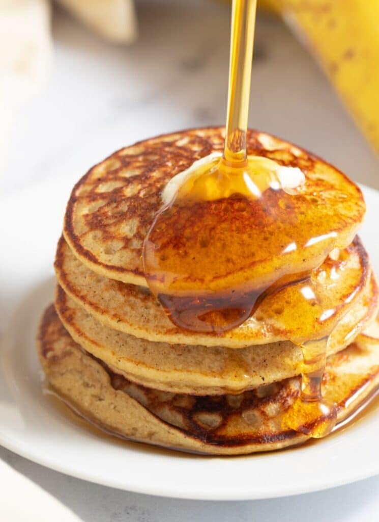 banana pancakes with syrup being poured on top