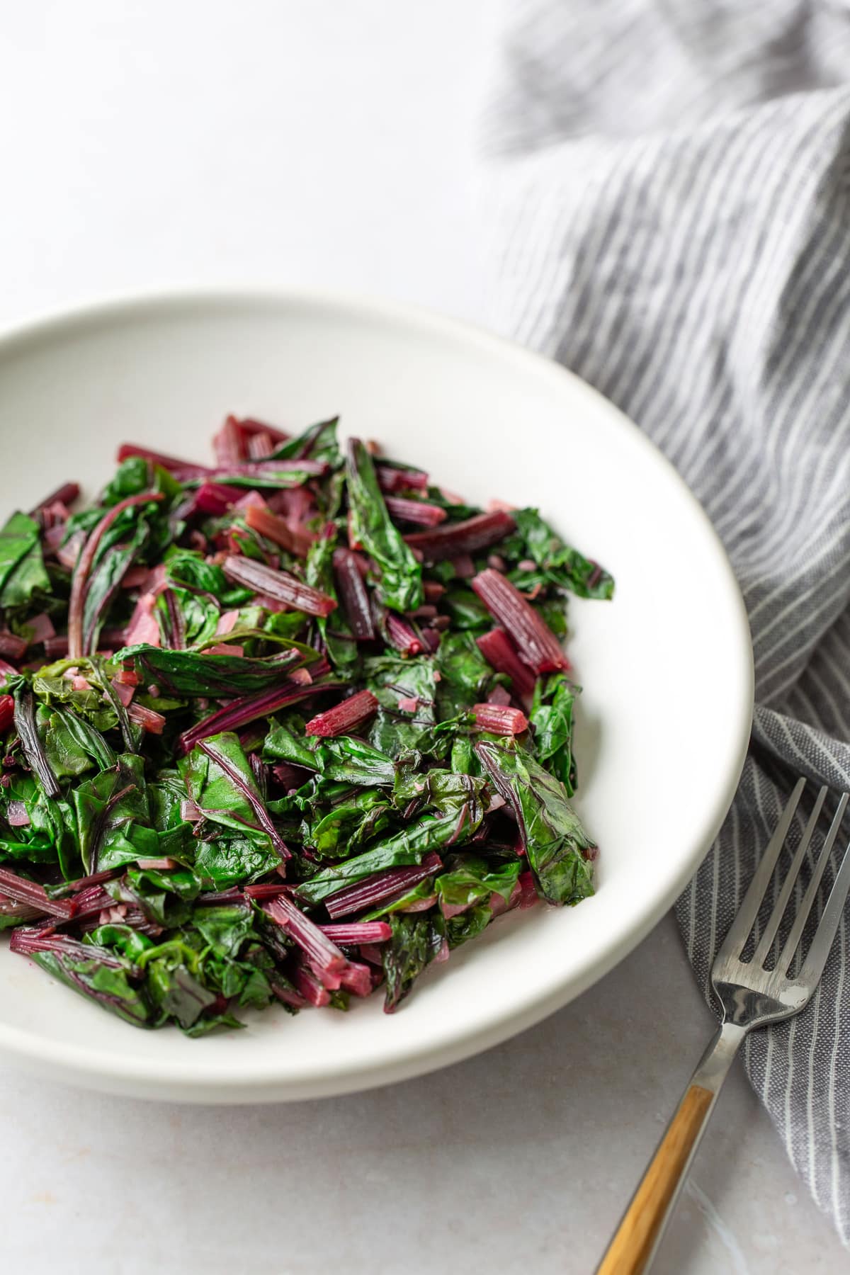 beet greens in white plate with fork on the side