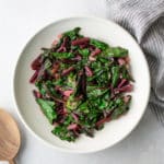 sauteed beet greens in white plate with spoon on side