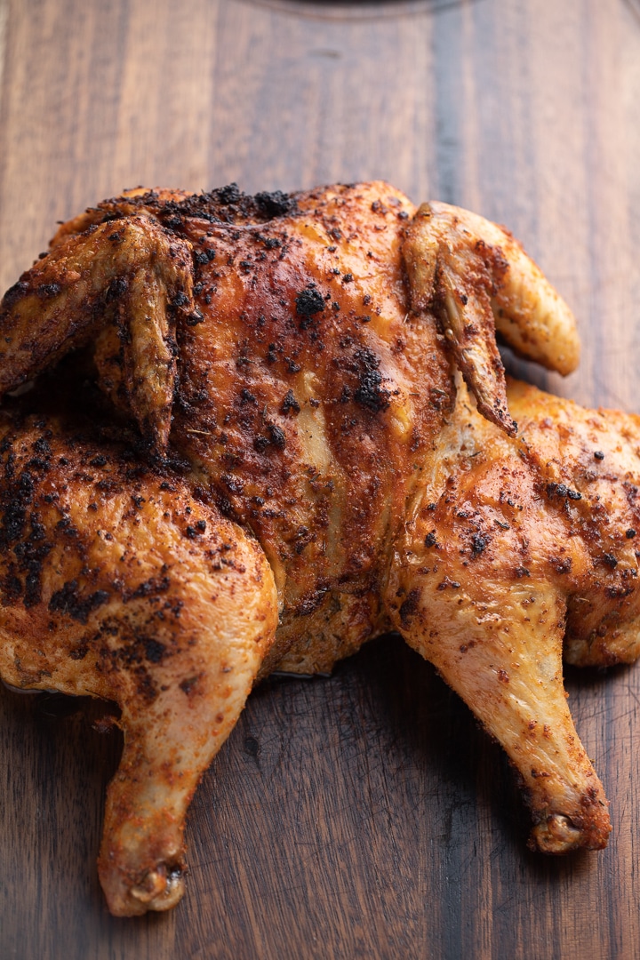 A fried spatchcoked chicken on a wooden work top