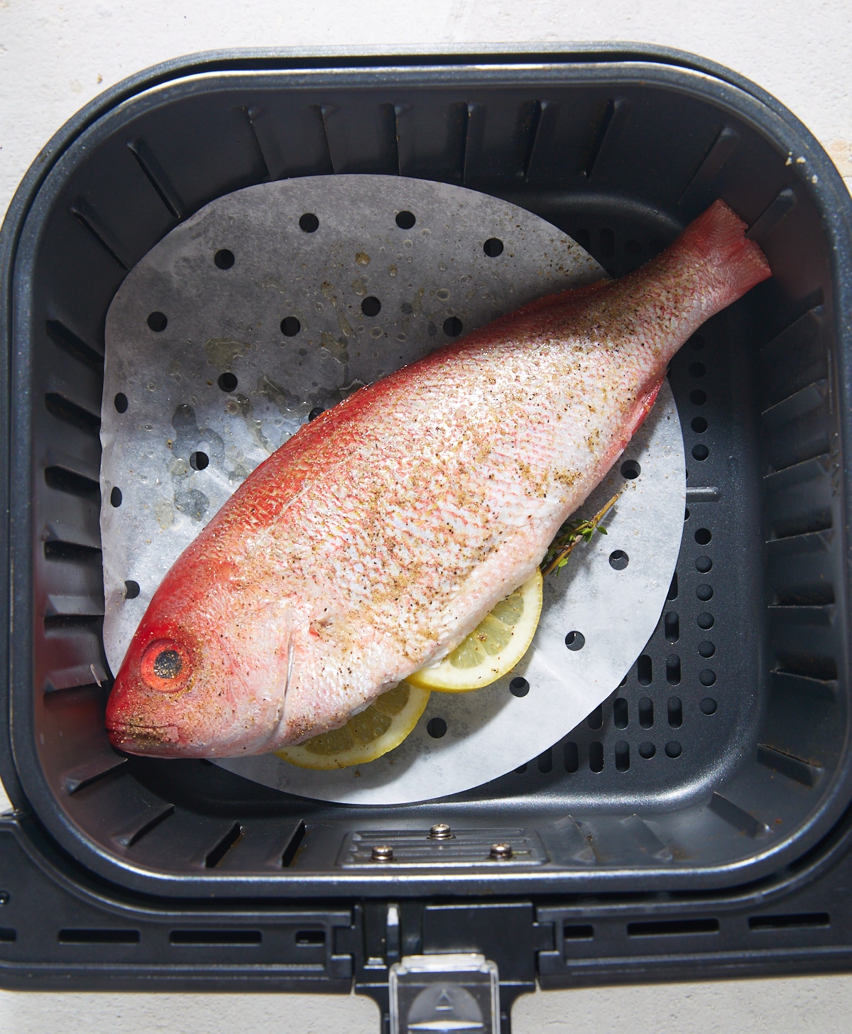 The whole fish in the air fryer basket before being cooked.