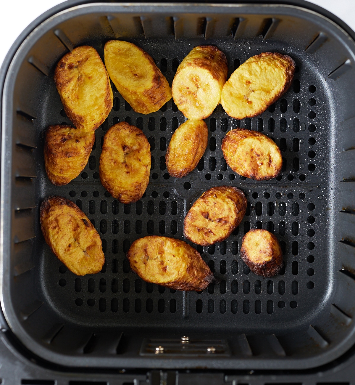The plantains in the air fryer basket after being cooked.