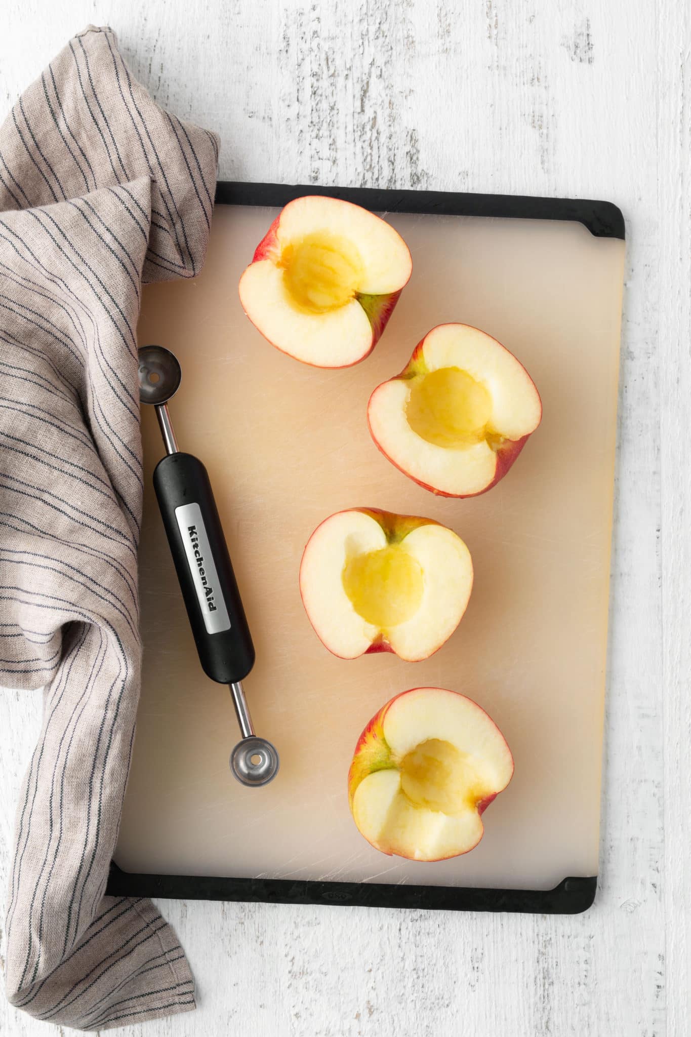 apples that have been cut in half and cored on baking sheet