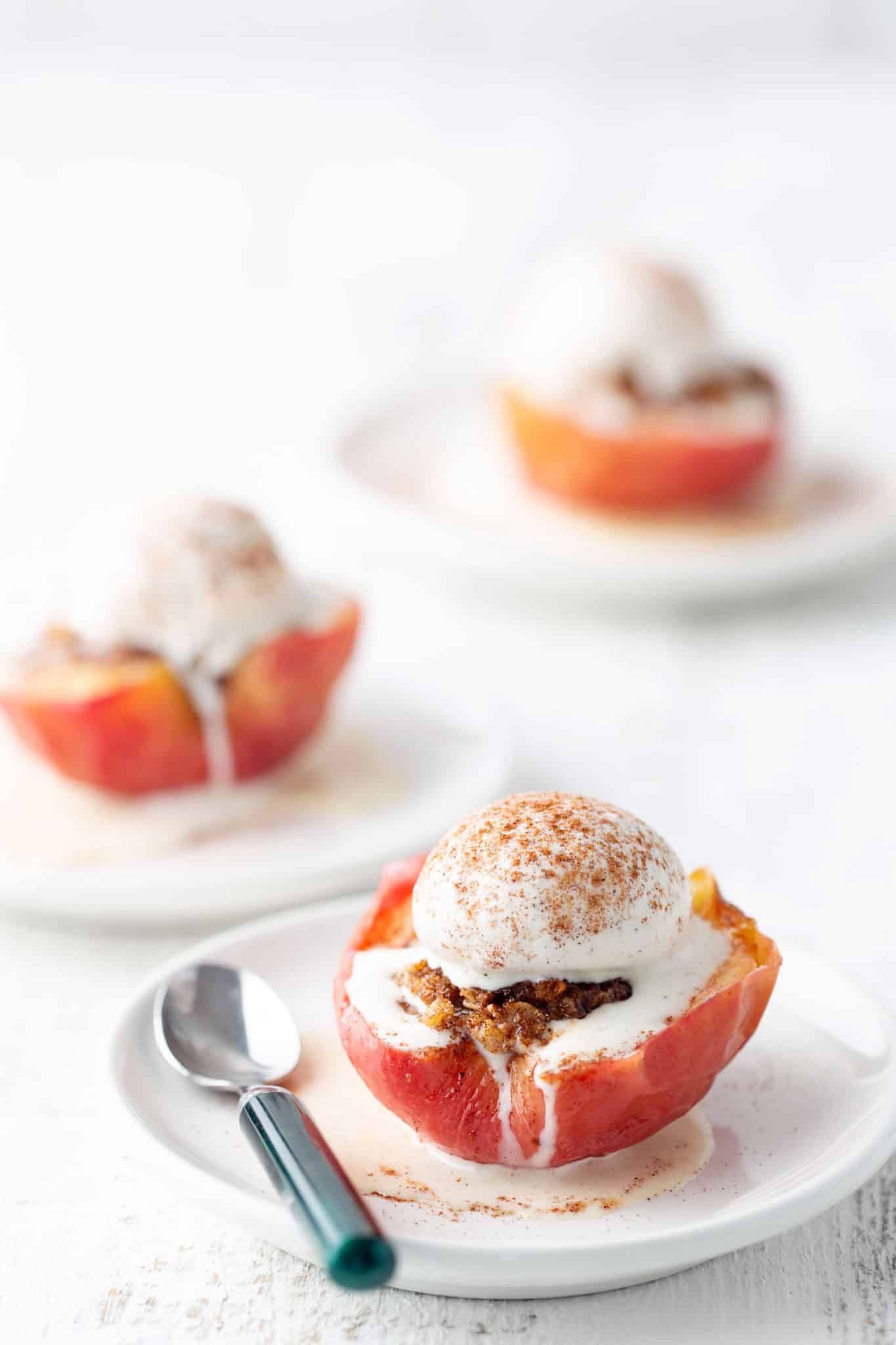 baked air fryer apples on white plate with spoon beside it topped with ice cream