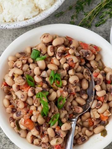 Blackeye peas served in a bowl next to a side dish of rice.