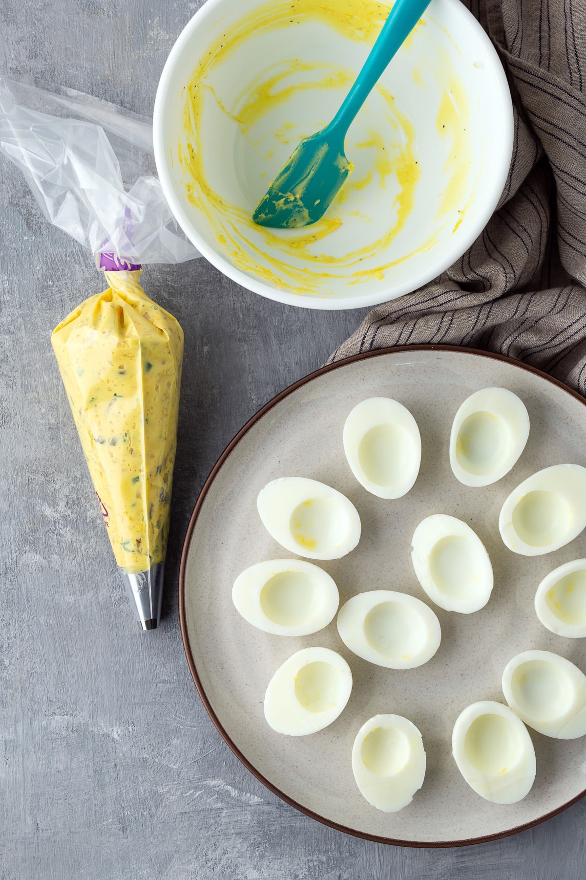 deviled eggs in a piping bag next to egg white halves