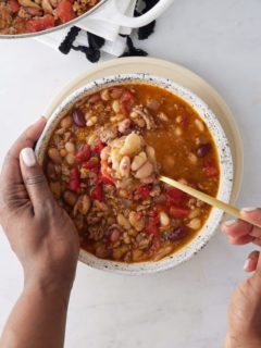 overhead of someone eating 15-bean soup with a spoon