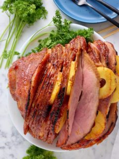 Fresh baked ham plated on a platter on the table.