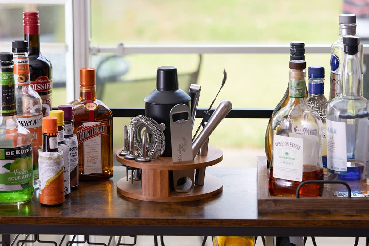 liquors, liquers, and home bar essentials on bar cart in front of window
