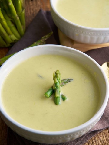 cream of asparagus soup in bowl with asparagus garnish on top