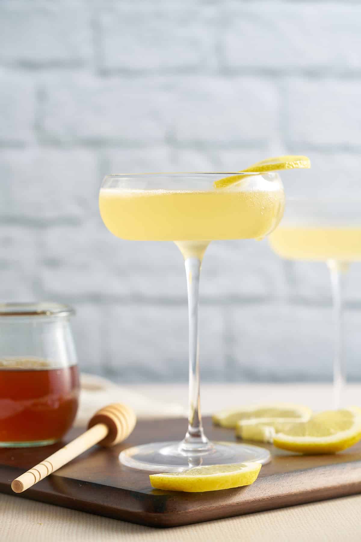 the cocktail in a glass with honey syrup next to it
