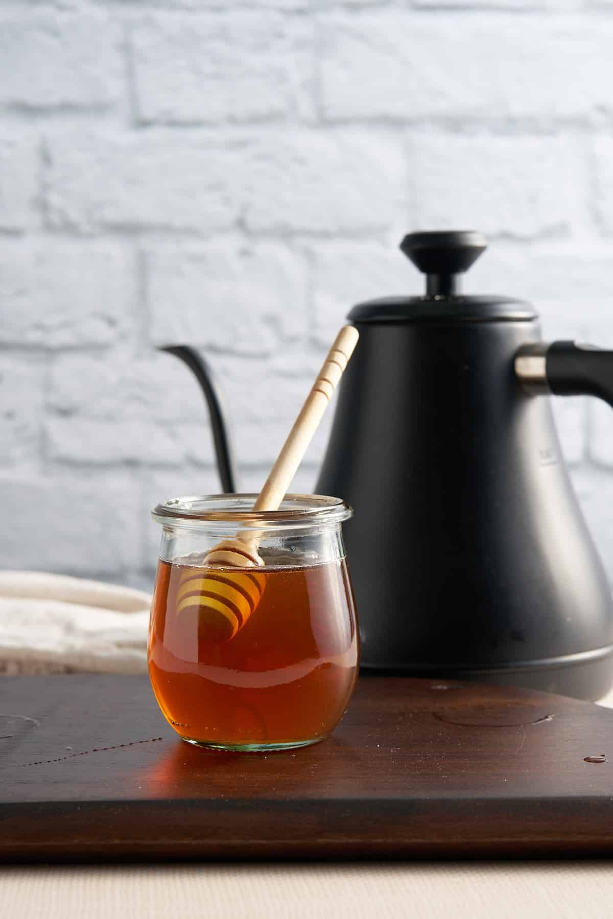 honey syrup in conatiner with hot water kettle behind it