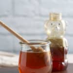 honey simple syrup in glass container in front of a honey bear container