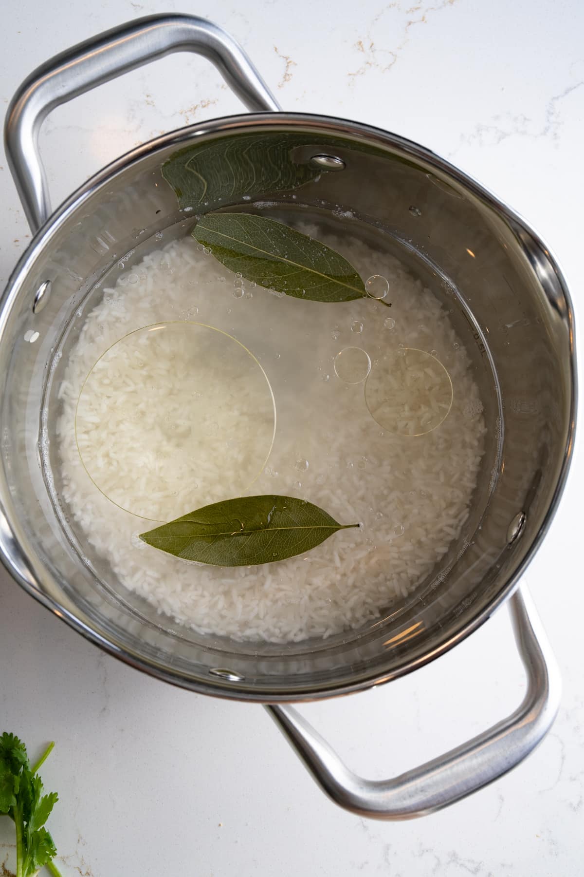 rice, water, oil, and bay leaves in pot