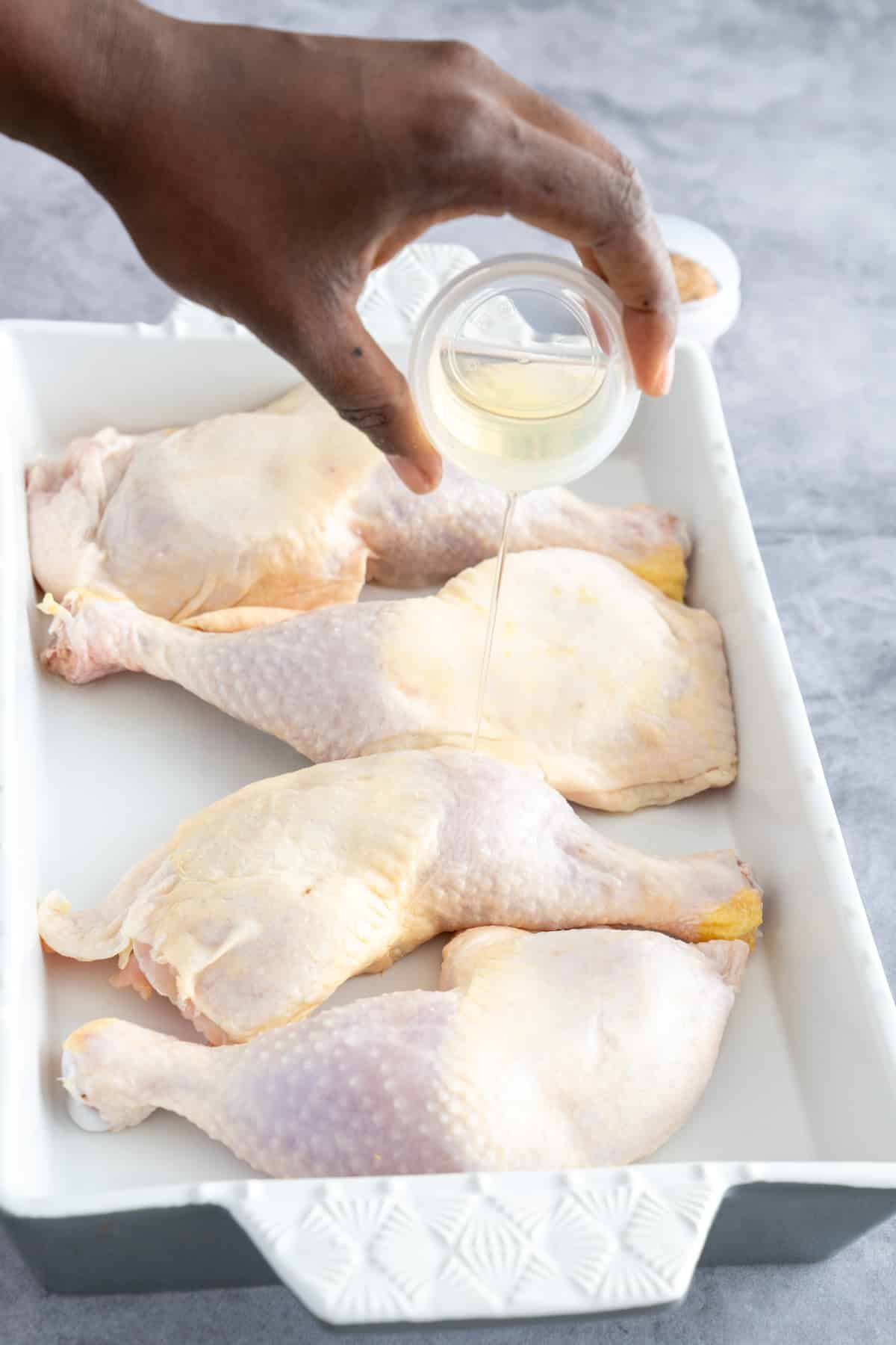 putting olive oil over the chicken while it's in the baking pan