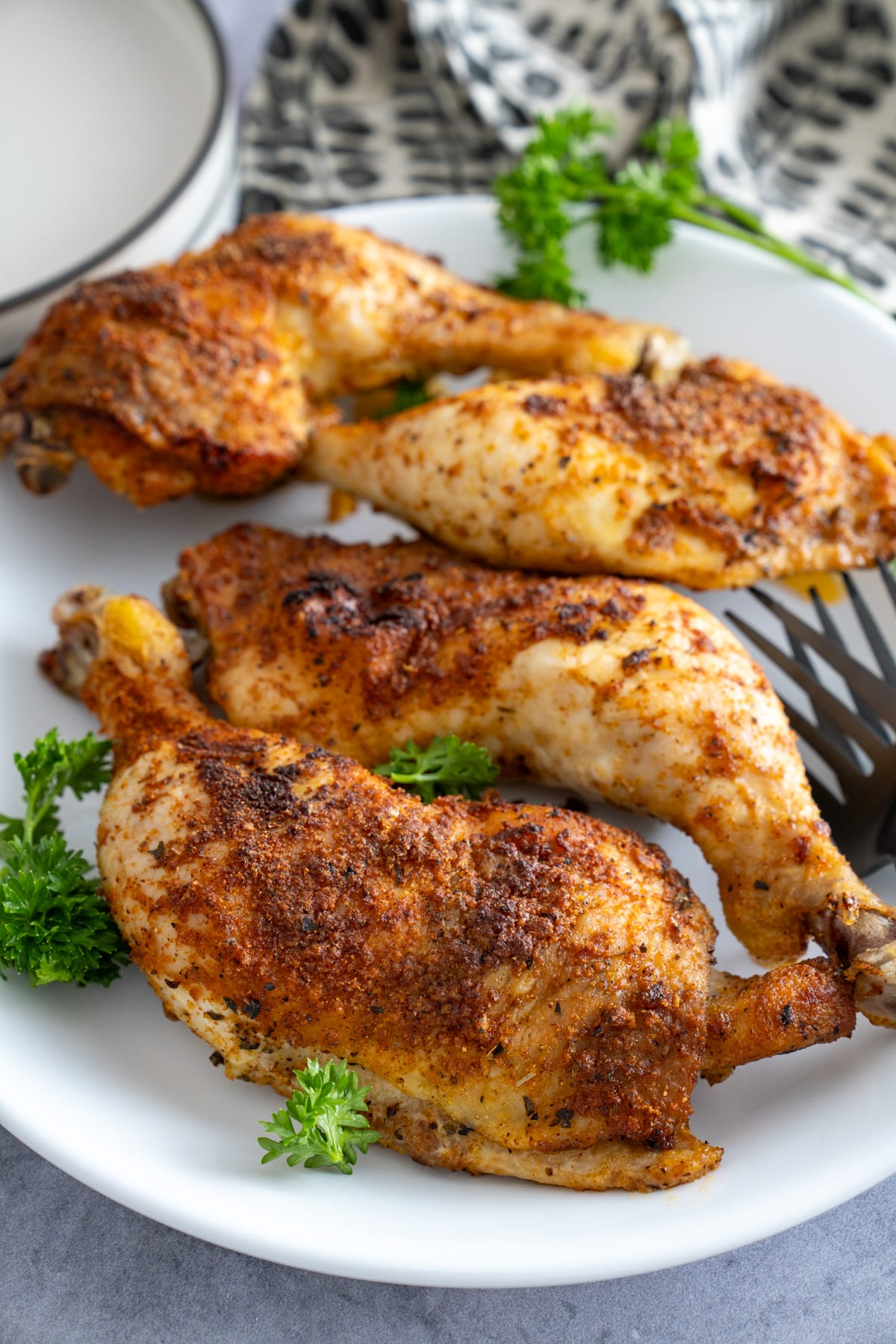 chicken leg quarters on plate with parsley around it