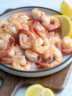 poached shrimp on a plate surrounded by lemons