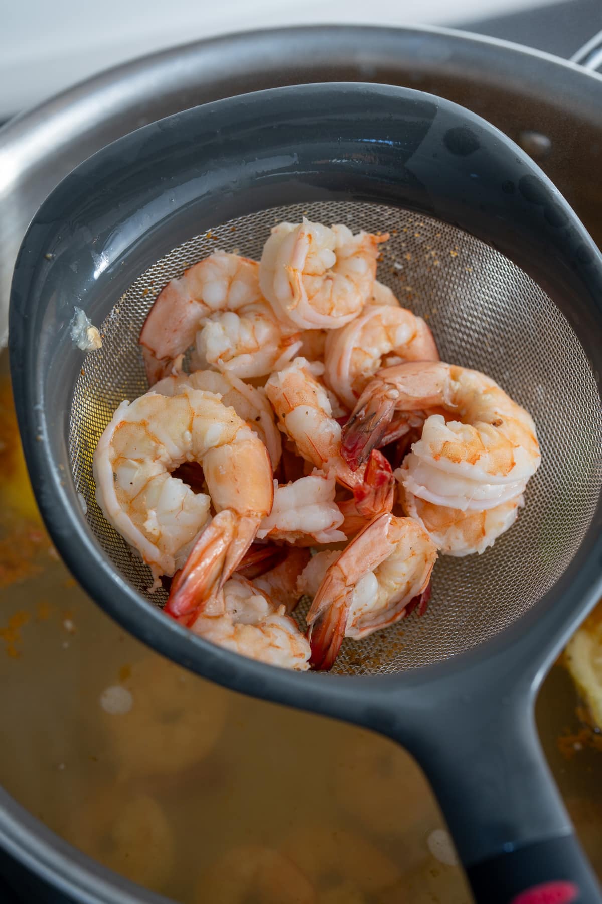 shrimp on colander taking it out of poaching liquid