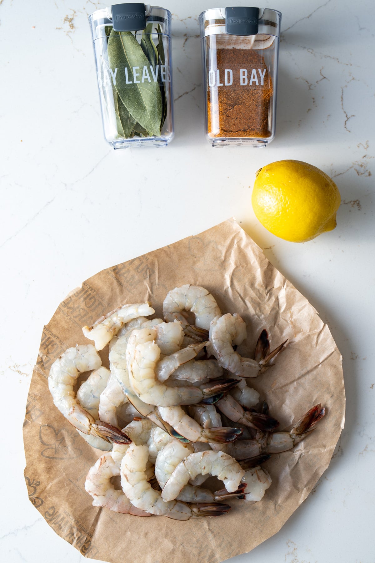 ingredients for poaching shrimp on background, shrimp. lemon, old bay, bay leaves