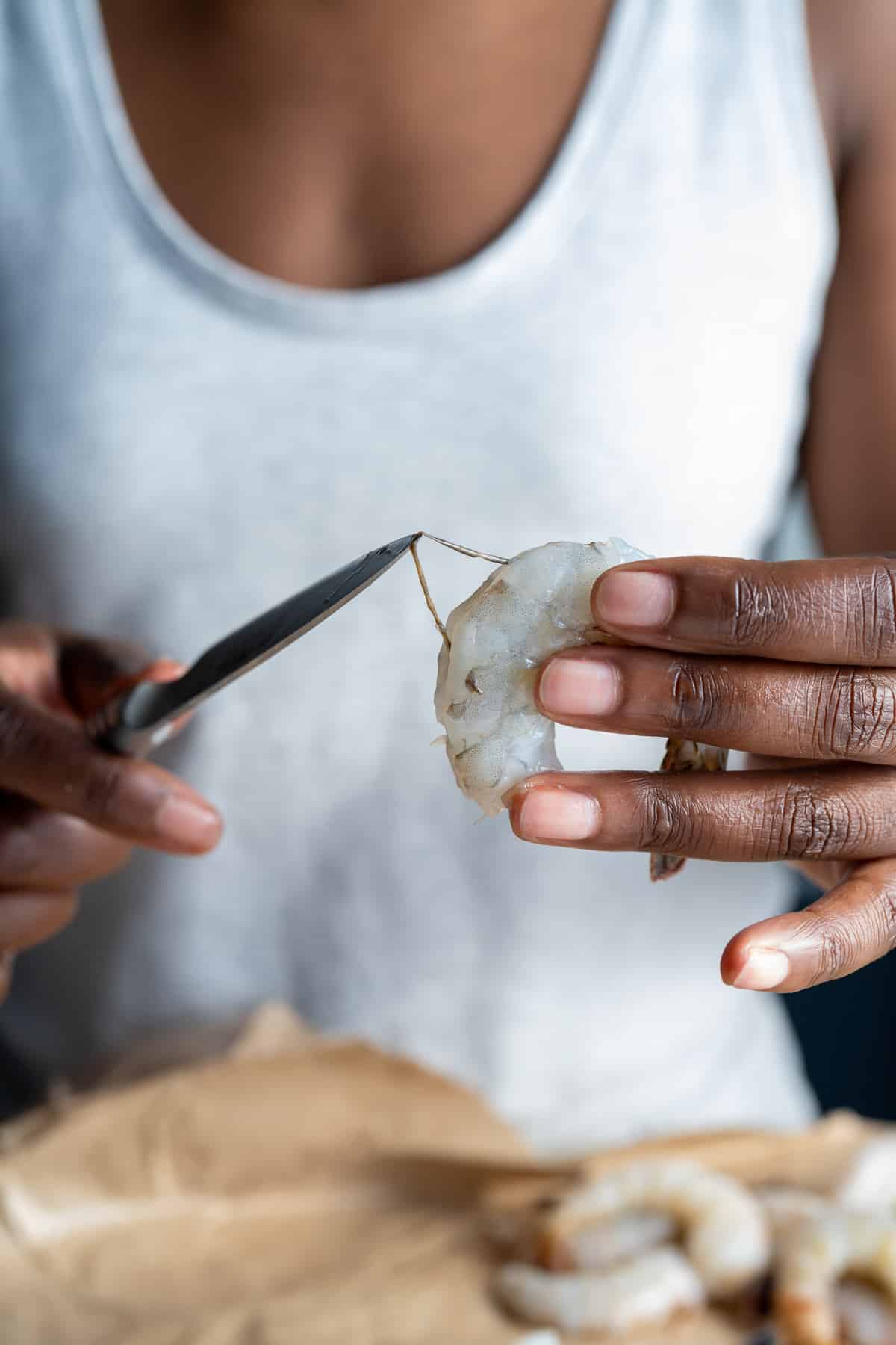 person removing vein from shrimp