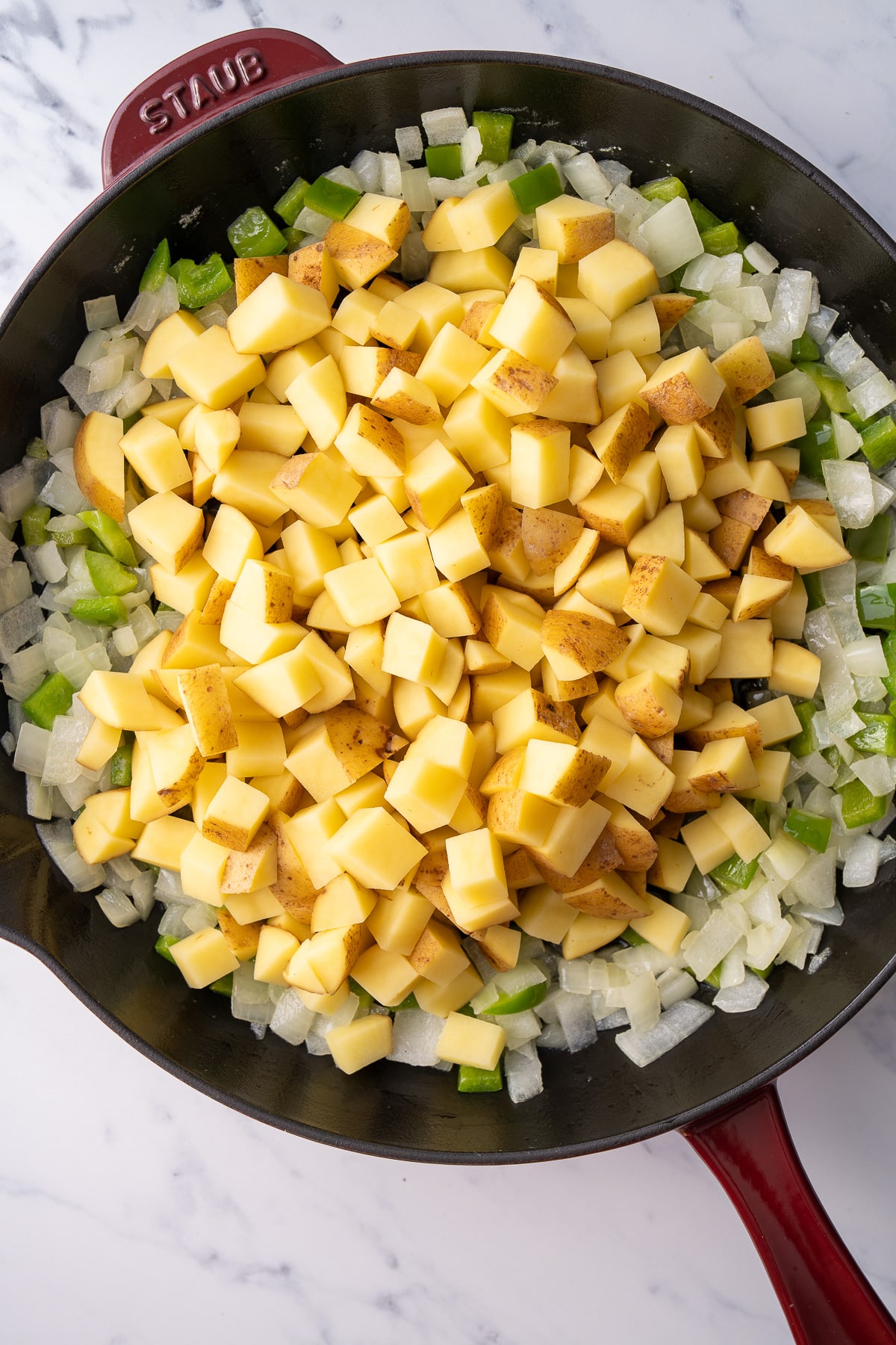 potatoes and green peppers in cast iron pan