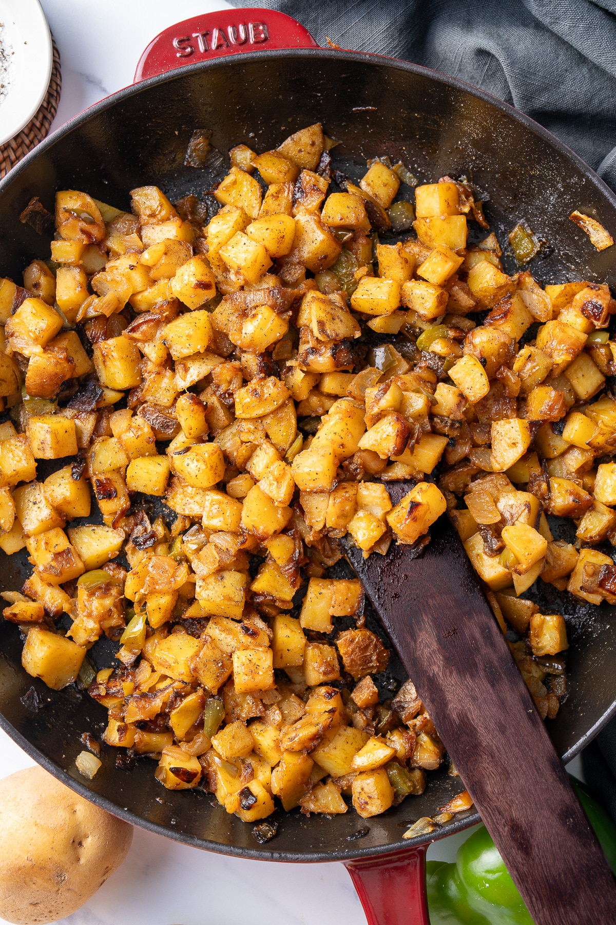 smothered potatoes in cast iron skillet with wooden spatula sticking out