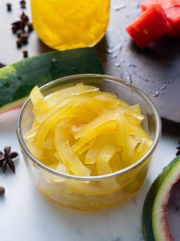 pickled watermelon rind in glass container with watermelon peel on side