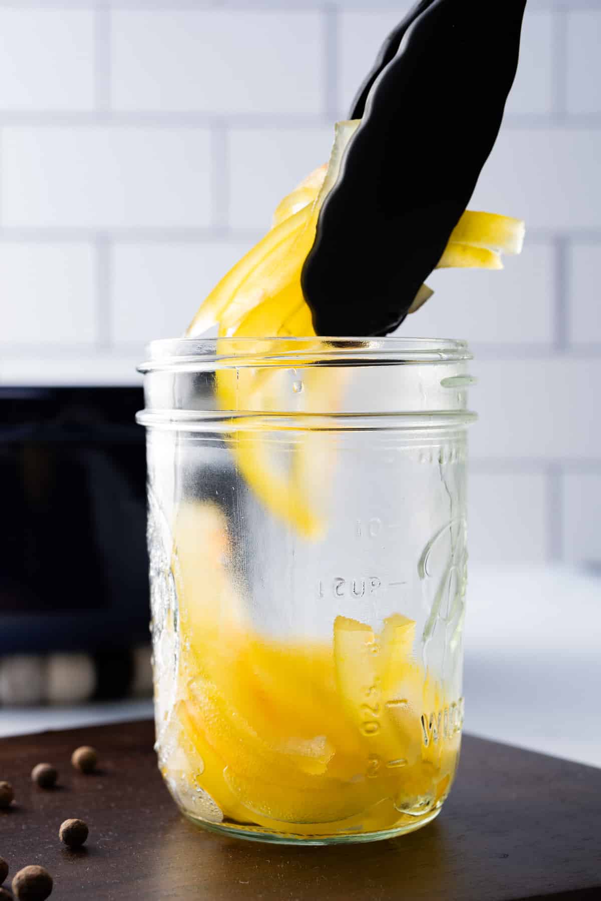 tongs putting pickled watermelon rind in jars