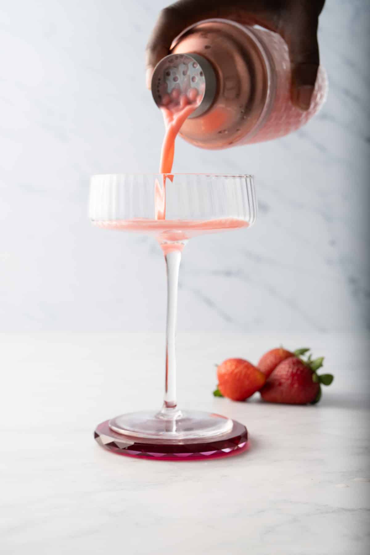 pink lady cocktail being poured into a glass