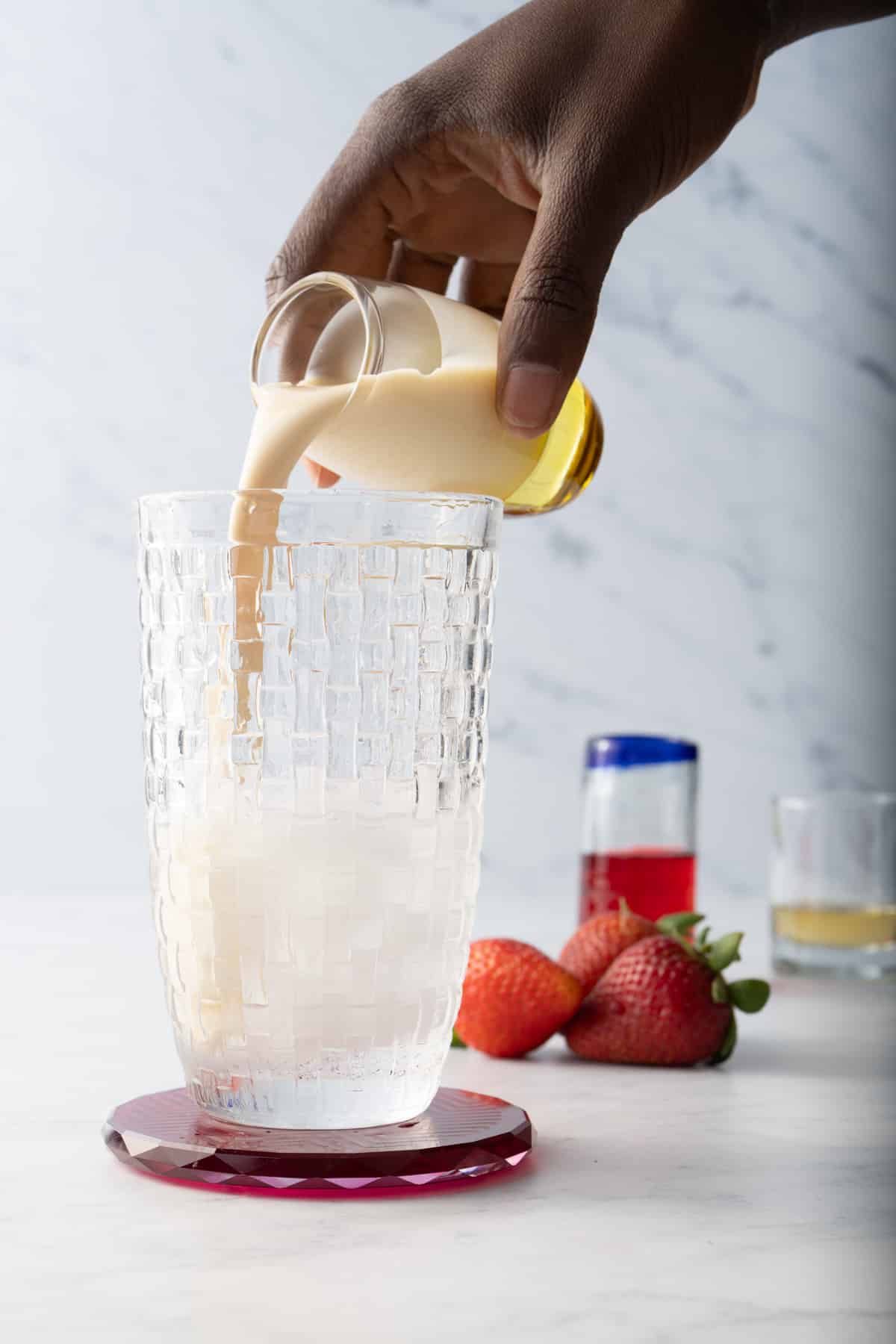 adding ingredients to cocktail shaker. pouring evaporated milk in. 