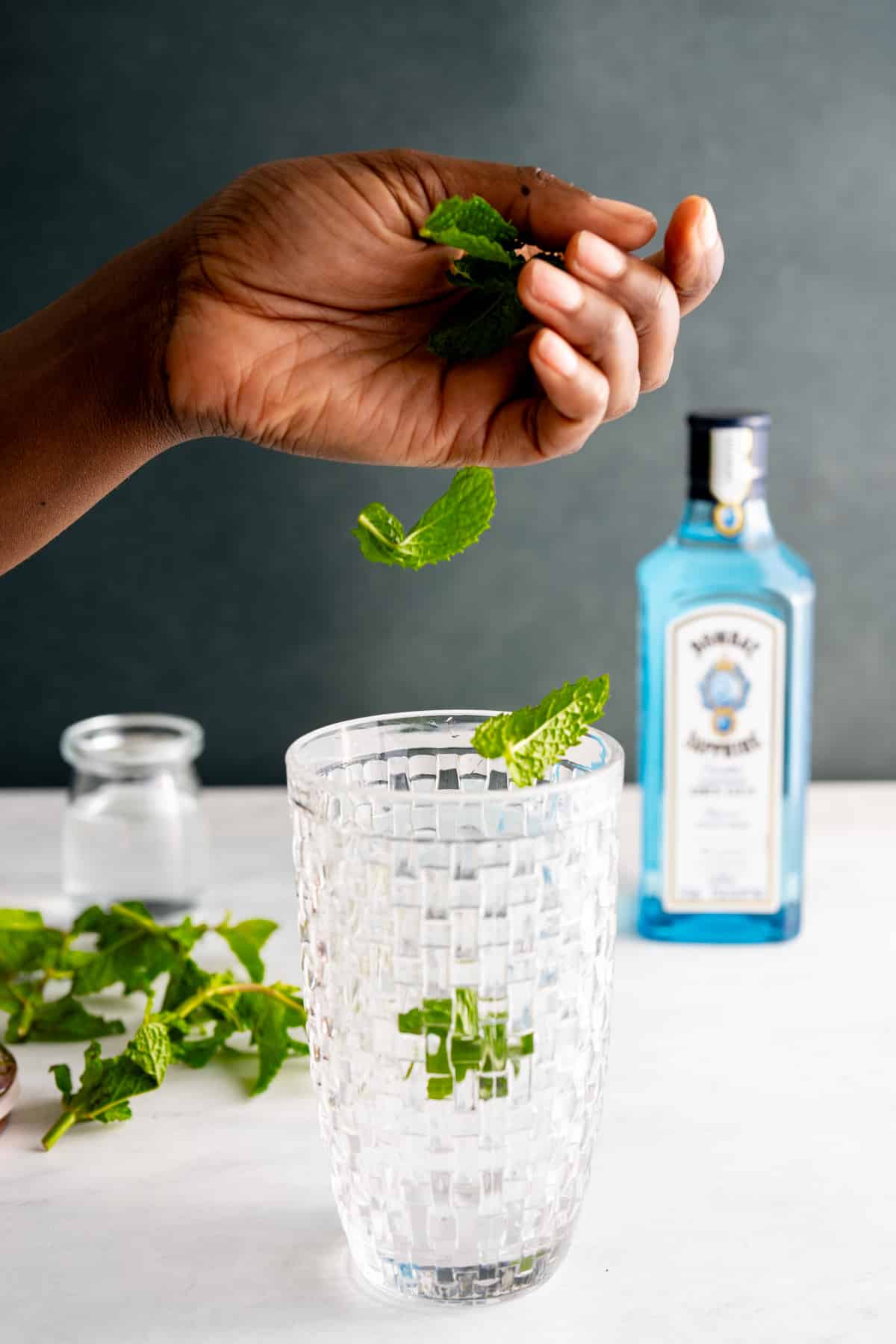 hand dropping mint into cocktail shaker