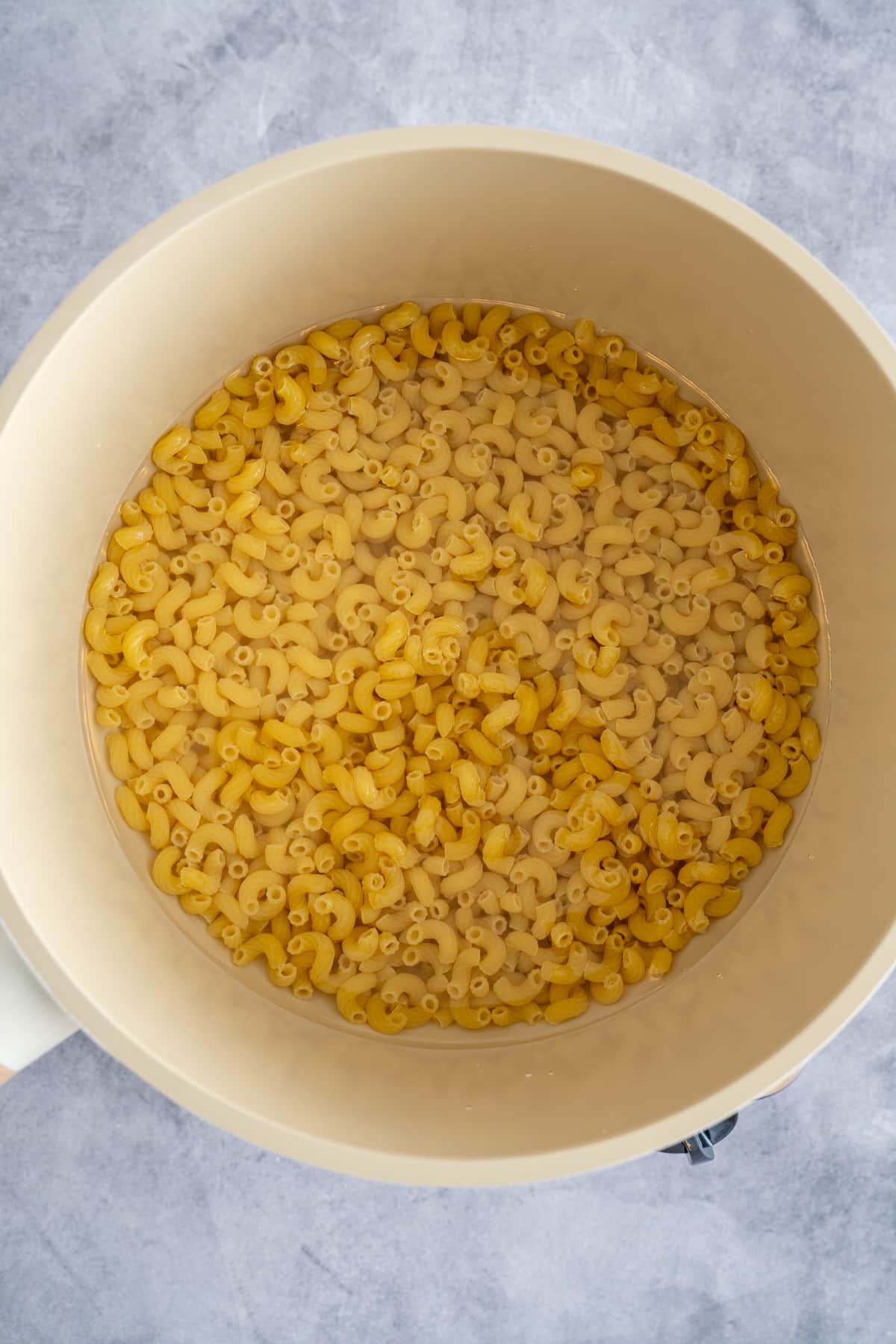 elbow macaroni in pot covered by water