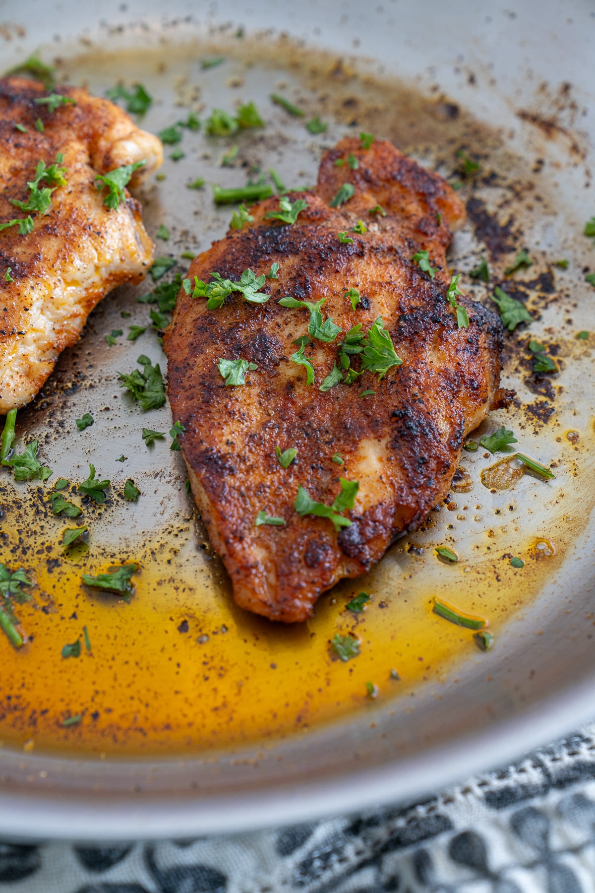 pan seared chicken breast filet in skillet garnished with parsley