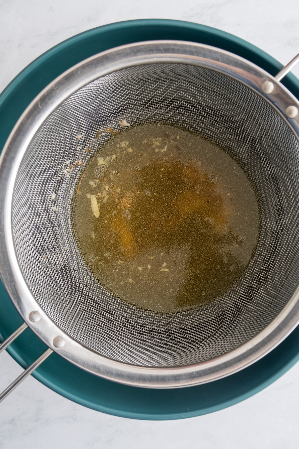 strained broth with strainer over bowl