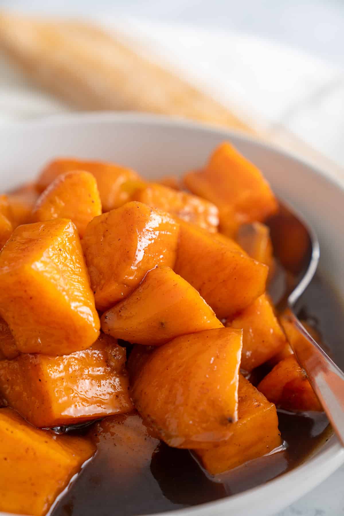 close up photo of candied sweet potatoes with spoon sticking out