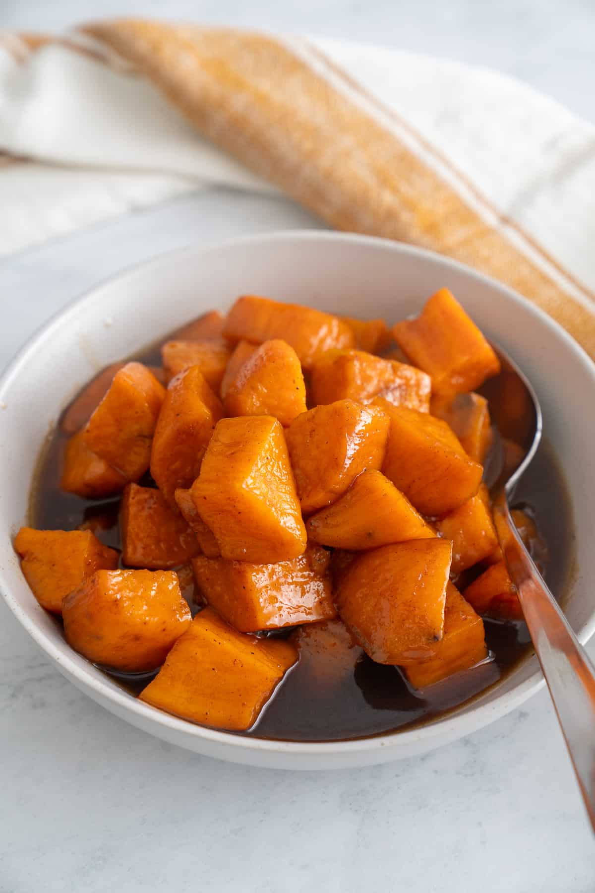 candied sweet potatoes in bowl with spoon sticking out