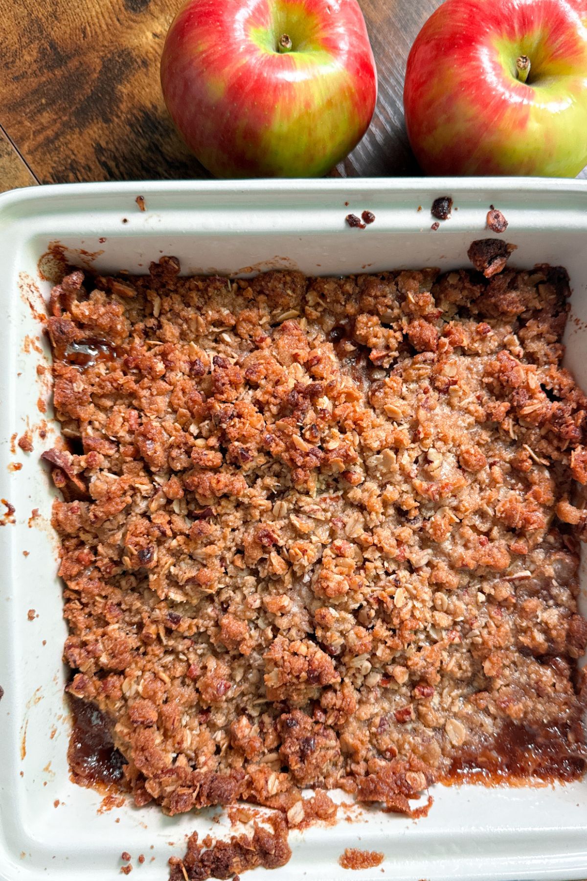 apple crisp in white baking dish with apples on side