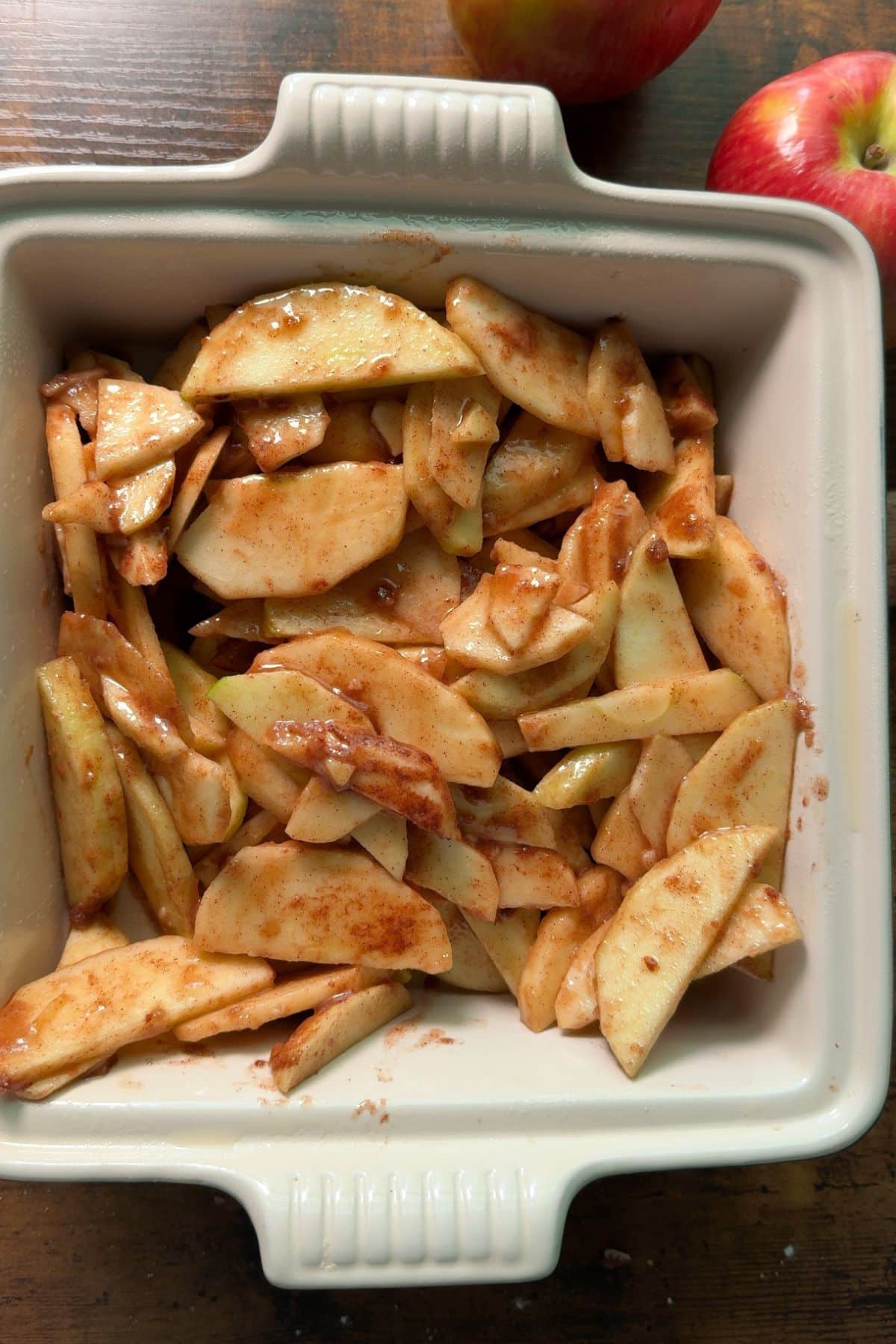 apple slices coated in brown sugar and flour and spices in baking dish