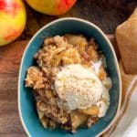 bowl of apple crisp with ice cream on top and apples on side