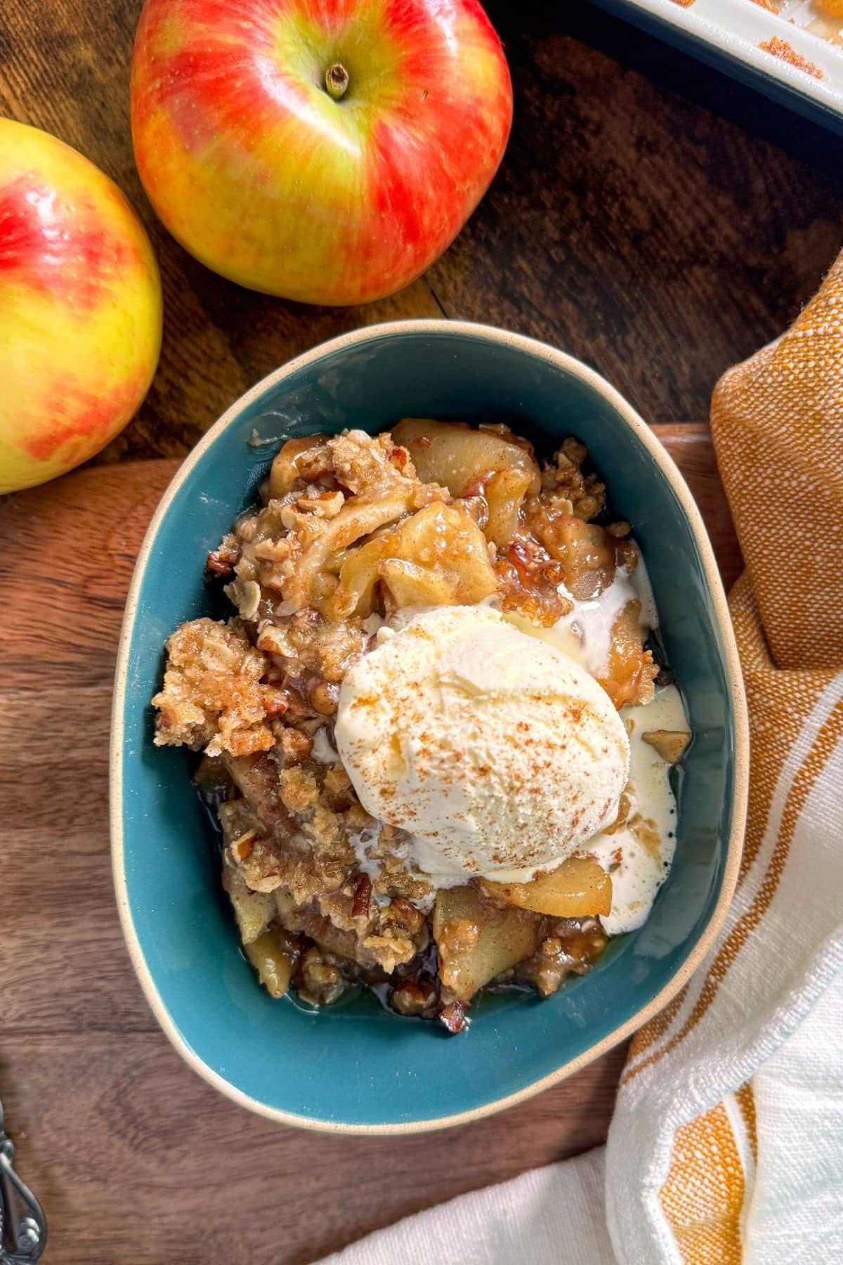 bowl of apple crisp with ice cream on top and apples on side