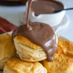 chocolate gravy being poured over biscuits